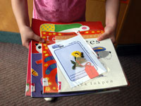 young child holding books with card on top